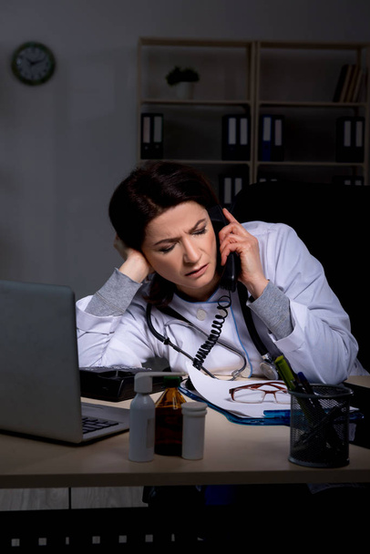 Aged female doctor working at night shift  - Foto, Bild