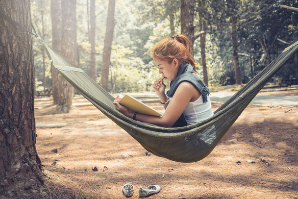 Mulheres sentadas a ler. Na cama de rede. Na atmosfera natural do parque
 - Foto, Imagem