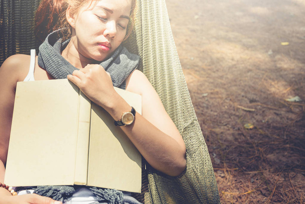 Frauen schlafen beim Lesen. in der Hängematte. in der natürlichen Atmosphäre des Parks - Foto, Bild
