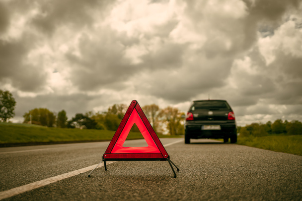 Ένα προειδοποιητικό τρίγωνο μπροστά από ένα αυτοκίνητο με κατάρρευση σε μια πλευρική λωρίδα - Φωτογραφία, εικόνα