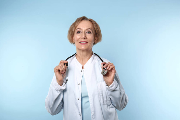 Beautiful female doctor on color background - Foto, imagen
