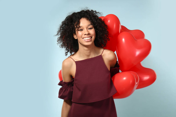 Happy African-American woman with air balloons on color background - Photo, image