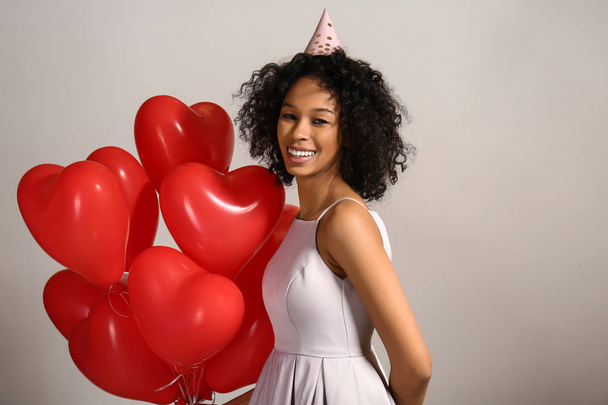 Happy African-American woman with air balloons on grey background - Foto, Imagem