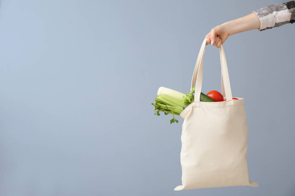 Female hand with eco bag on grey background. Zero waste concept - Photo, Image