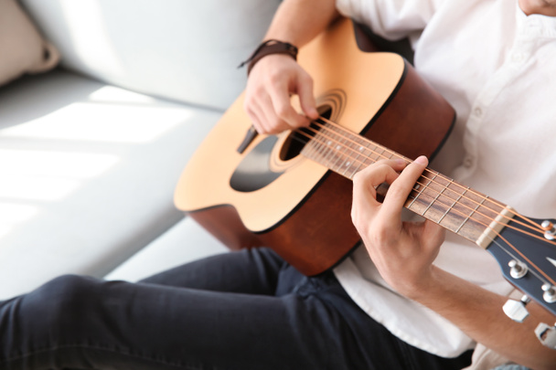 Handsome young man playing guitar at home - Fotó, kép