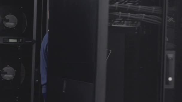 Άνθρωπος που συνεργάζεται με διακομιστές στο σύγχρονο κέντρο δεδομένων χρησιμοποιώντας φορητό υπολογιστή - Πλάνα, βίντεο