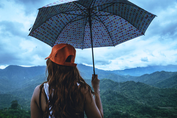 Οι ασιατικές γυναίκες ταξιδεύουν χαλαρώστε στις διακοπές. Οι γυναίκες στάθηκαν στη βροχή. - Φωτογραφία, εικόνα
