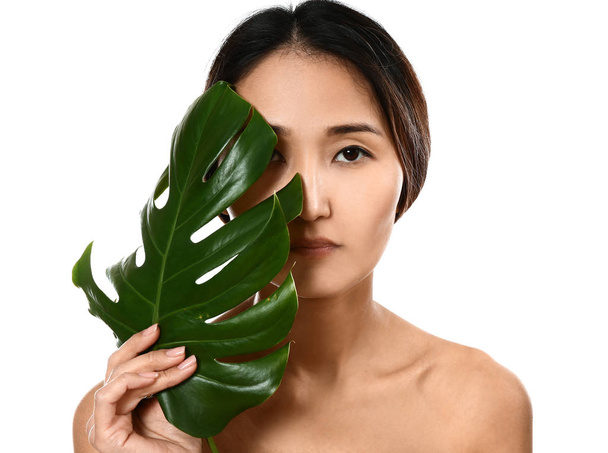 Asian woman with tropical leaf on white background - Foto, afbeelding