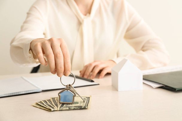 Real estate agent with key from house and money at table - 写真・画像