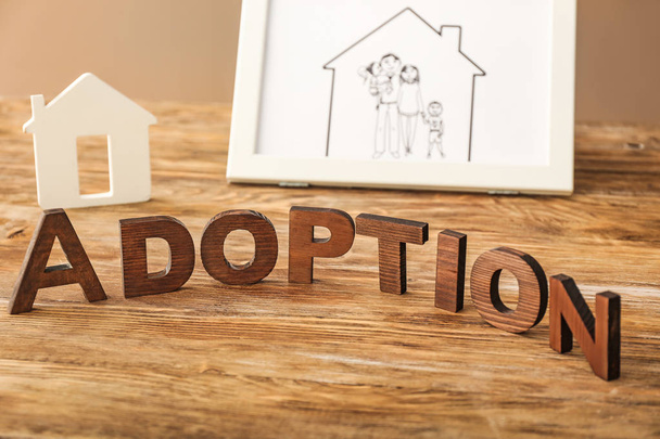 Słowo Adopcja, figura domu i rysunek rodziny na stole - Zdjęcie, obraz
