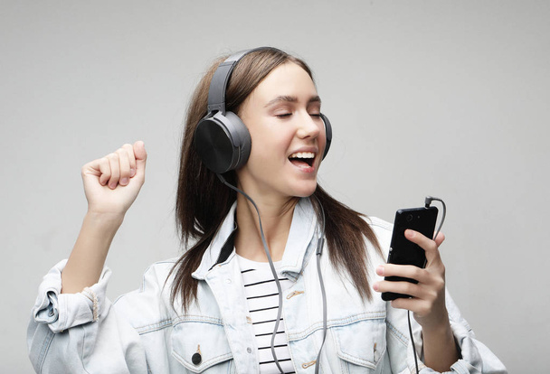 Beautiful young woman listening to music in headphones with smartphone  - Фото, изображение
