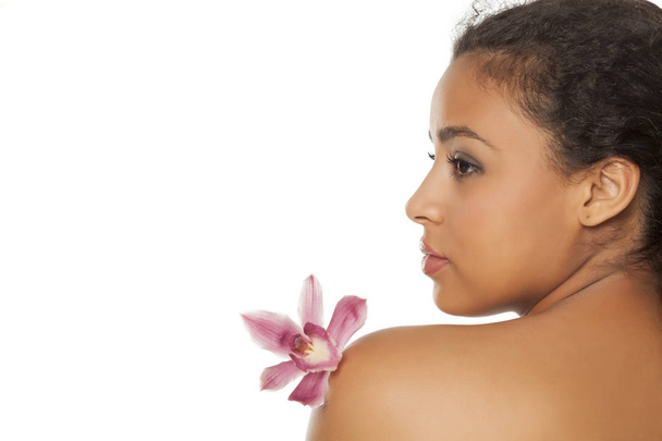 白い背景に蘭を持つ若い美しい黒い肌の女性のプロフィール - 写真・画像