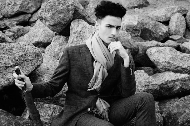   fashionable young man sitting on the rocks near the sea - Fotó, kép