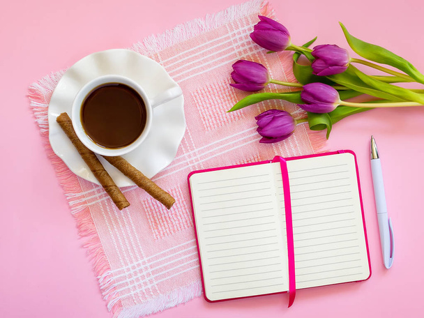 Cup with coffee, two coffee rolls, pink tulips and paper notebook - Valokuva, kuva