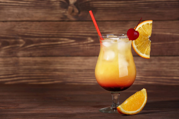 Glass of tasty Tequila Sunrise cocktail on wooden background - Photo, Image