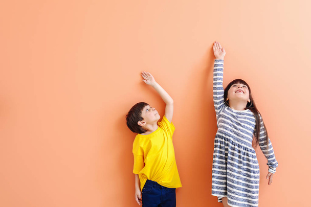 Crianças pequenas bonitos medindo altura perto da parede de cor
 - Foto, Imagem
