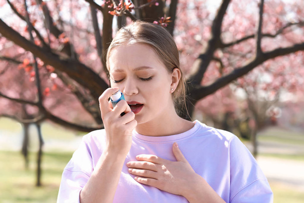 Γυναίκα με συσκευή εισπνοής που έχει κρίση άσθματος την ημέρα της άνοιξης - Φωτογραφία, εικόνα