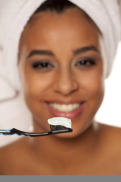 portrait d'une heureuse jeune femme à la peau foncée posant avec brosse à dents et pâte à dents sur fond blanc
 - Photo, image
