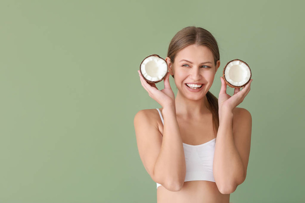 Beautiful young woman with coconut on color background - Photo, Image