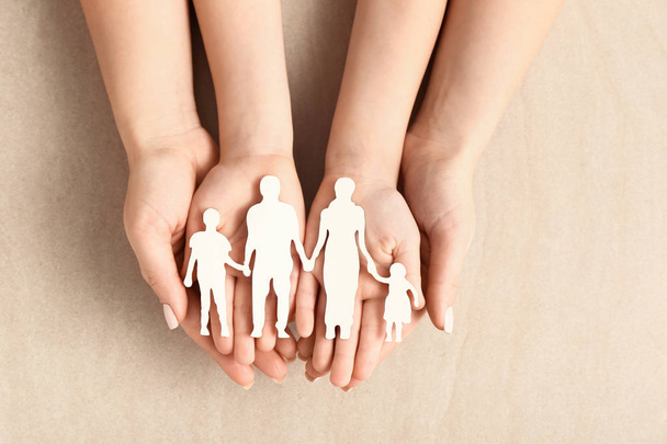 Hands of woman and child with figure of family on light background. Adoption concept - Photo, Image
