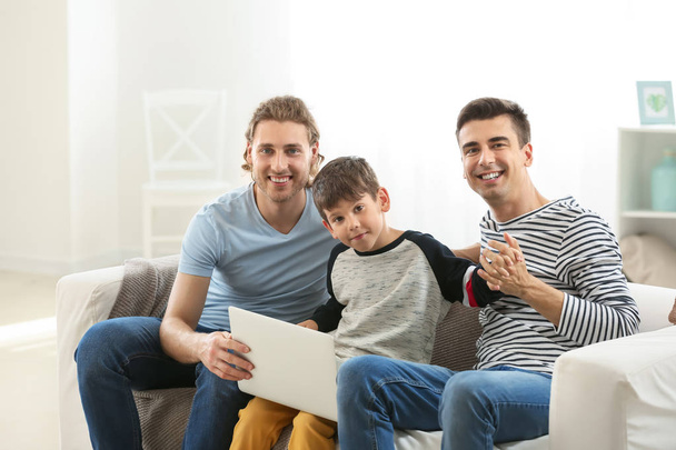 Happy gay couple and adopted child with laptop at home - Photo, Image