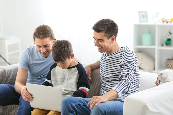Gelukkig homo paar en geadopteerd kind met laptop thuis - Foto, afbeelding