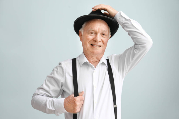Portrét staršího muže v klobouku na světle pozadí - Fotografie, Obrázek