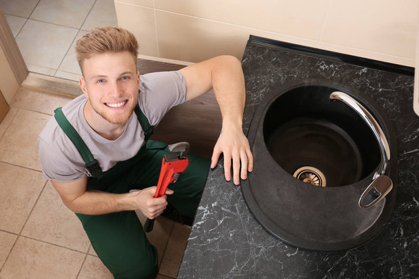 Plumber repairing sink in kitchen - Foto, afbeelding