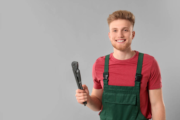 Handsome plumber on grey background - Foto, imagen