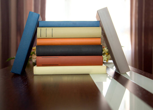 kleurrijke Boekentoren op houten tafel met ruimte om te schrijven - Foto, afbeelding
