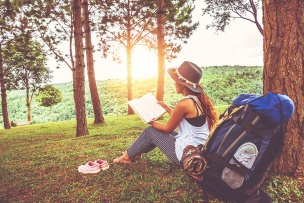 asiatische Frauen reisen entspannt in den Urlaub. sitzen und Bücher über Grünland im Park lesen. Bildung, Sommer, Land, lesen Sie ein Buch, Buch, schreiben Sie eine Notiz, Tagebuch. - Foto, Bild