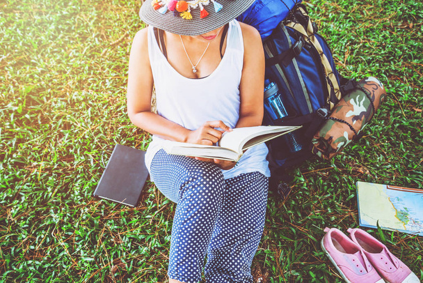 Asian women relax in the holiday. Sit read books on grassland in the park. education, read a book, book, Write a note, diary, nature, outdoor, holiday, sport, exercise, relax, travel Thailand, summer. - Fotografie, Obrázek