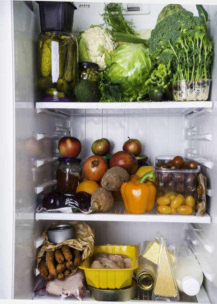 Close-up van volledige koelkast, verse en kleurrijke groenten, fruit, dayrt product in de koelkast, rijke voeding voedsel - Foto, afbeelding