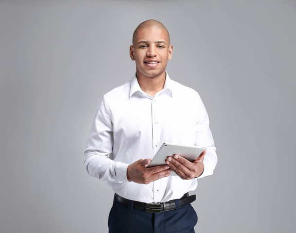 Красивий афро-американський бізнесмен з планшетним комп'ютером на сірому фоні - Фото, зображення