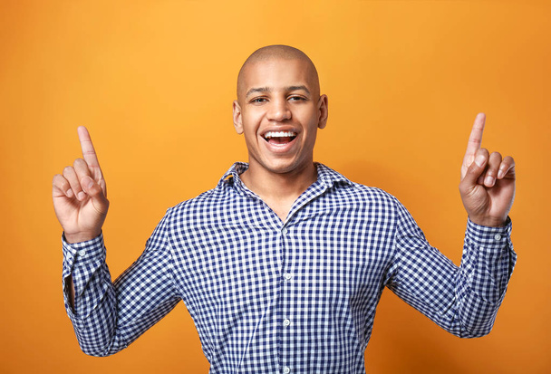 Handsome African-American man pointing at something on color background - Fotó, kép