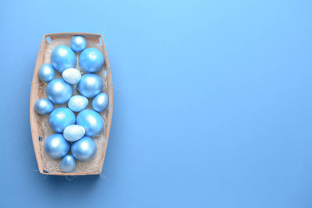 Κουτί με όμορφα Πασχαλινά αυγά στο φόντο του χρώματος - Φωτογραφία, εικόνα