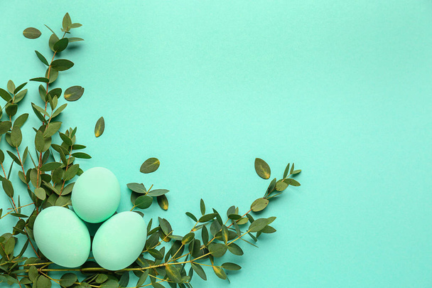 Beautiful Easter eggs with green leaves on color background - Photo, Image