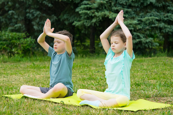 boy and girl relax together on the gymnastics Mat, doing yoga, outdoors - Fotografie, Obrázek