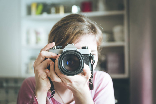 Young girl is taking a picture with a vintage camera, retro styl - 写真・画像
