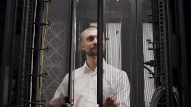 Ez mérnök dolgozó laptop előtt nyitott szerver rack a szobában - Felvétel, videó