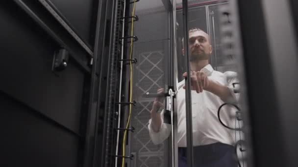 Człowiek otwierający stojak serwerowego systemu hostingowego w Big Data Center - Materiał filmowy, wideo