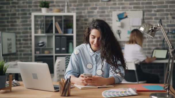 Veselá dívka používající smartphone dotykové obrazovky pracující v kanceláři na stole - Záběry, video
