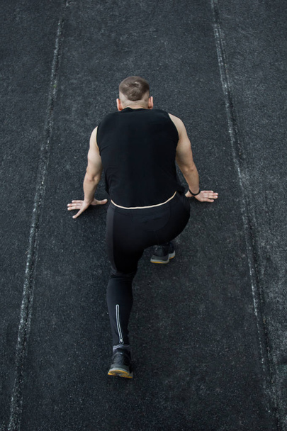 caucasian man doing a sprint start. running on the stadium on a track. Track and field runner in sport uniform. energetic physical activities. outdoor exercise, healthy lifestyle. vertical top view - Foto, imagen