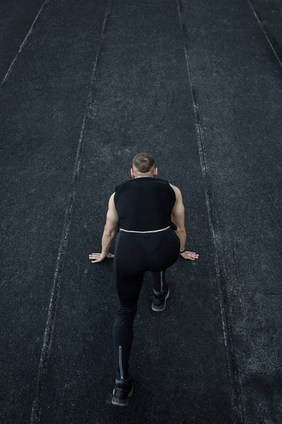 caucasian man doing a sprint start. running on the stadium on a track. Track and field runner in sport uniform. energetic physical activities. outdoor exercise, healthy lifestyle. vertical top view - Fotografie, Obrázek