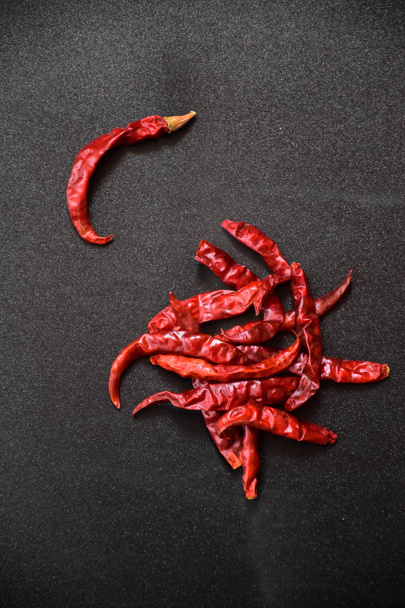 a bunch of red hot chili peppers on a black background - Foto, afbeelding