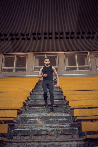 Caucasian man trains in running on the stairs. Track and field runner in sport uniform training outdoor. athlete, top view. step exercise. steps down. vertical - Zdjęcie, obraz