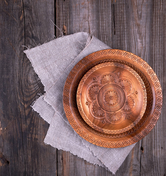 empty round brown carved decorative plate standing on a gray lin - Photo, Image