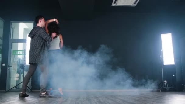 Ładna para tańczy przed czarnym tłem w studiu tańca - Materiał filmowy, wideo