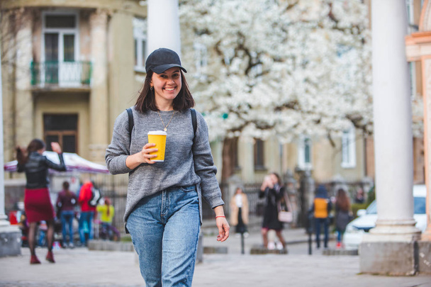 fiatal elegáns nő sétál az utcán kávéscsészével - Fotó, kép