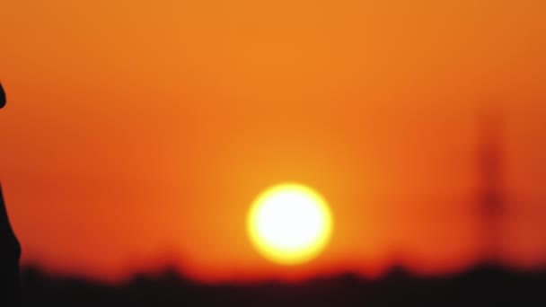 Mladý pár jemně držící ruce na pozadí velké oranžové sluneční plochy - Záběry, video